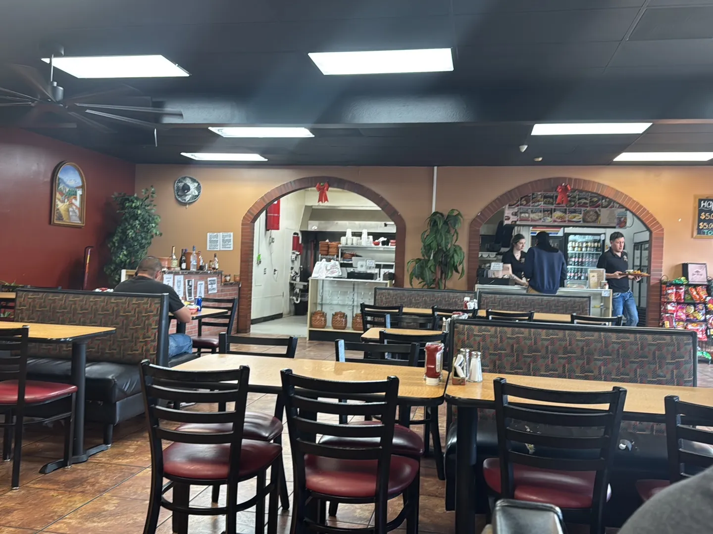 San Julián's dining room with brick archways, terracotta tile floors, peach and red walls, and patterned booth seating
